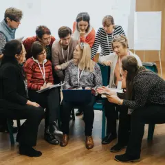 Lehrerinnen und Lehrer im Austausch während einer Hospitation in der Schule. Sie diskutieren und arbeiten an einem Laptop.