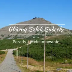 Główny Szlak Sudecki, 440 km. Widok na górę ze szczytem i budynkami, droga kamienista, zieleń.