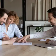 Para omawia z agentem warunki rezygnacji z wynajmu mieszkania i zwrotu kaucji, podpisując dokumenty.