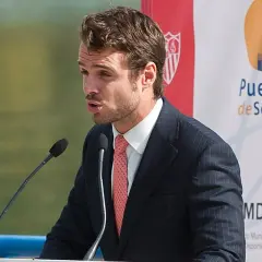 José María González de Caldas, con traje y corbata, habla en un atril con micrófonos. Fondo con logo de Puerto de Sevilla.