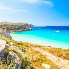 Paesaggio mozzafiato con le calette di Favignana, acque cristalline e barche all'ancora.