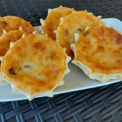 Sei formaggelle di formaggio dorate e invitanti, disposte su un piatto bianco.