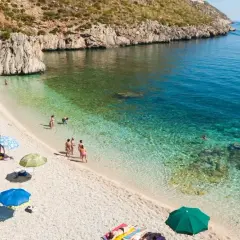 Piękna pogoda na Sycylii w październiku. Ludzie opalają się na kamienistej plaży, kąpią w krystalicznie czystej wodzie.
