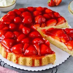 Eine saftige Erdbeertorte mit frischen Erdbeeren und Tortenguss, ein Stück wird herausgeschnitten.