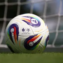 Piłka nożna PKO BP Ekstraklasa na trawie przed bramką.