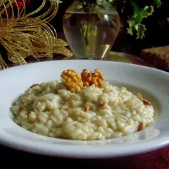 Kremowe risotto z gorgonzolą i orzechami włoskimi, ozdobione złotą dekoracją.
