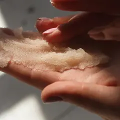 Dłonie trzymające domowy peeling cukrowy. Delikatne drobinki kuszą do domowego SPA.