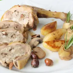 Délicieuse cuisse de pintade farcie, servie avec des pommes de terre rôties, des champignons et des cœurs d'artichauts garnis de romarin.