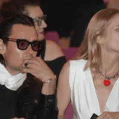 Magdalena Cielecka i Bartosz Gelner na widowni. Ona w białej sukni z naszyjnikiem w kształcie serca, on w skórzanej kurtce i okularach.