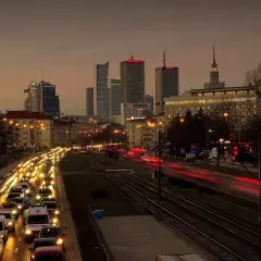 Warszawski krajobraz miejski o zmierzchu z korkiem ulicznym i światłami budynków.