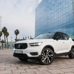 Białe Volvo XC40 z czarnym dachem zaparkowane przed nowoczesnym budynkiem z niebieskimi oknami.