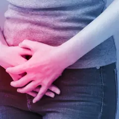 Osoba trzyma się za brzuch, odczuwając ból. Może to być objaw problemów z pęcherzem, które łagodzi ditropan.