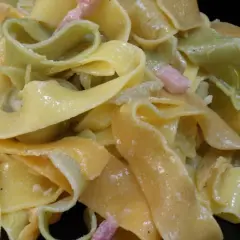 Pâtes larges, jaunes et vertes, nappées d'une sauce crémeuse et parsemées de lardons. Un délice de sauce carbonara.