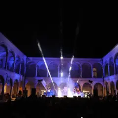 Concerto live sotto gli archi illuminati, un'atmosfera magica per la festa della musica a Brescia.