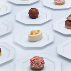 Collection de petits gâteaux raffinés, un véritable produit de luxe alimentaire, présentés sur des assiettes blanches.