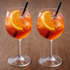 Dwa Aperol Spritz z pomarańczą i lodem, idealne aperol proporcje na drewnianym tle.