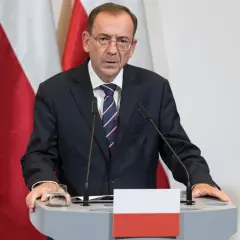 Mężczyzna w garniturze przy mównicy z polską flagą. Czy to odpowiedź na pytanie, dlaczego prezydent nie skorzystał z prawa łaski wobec skazanych urzędników państwowych?
