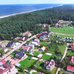 Widok z lotu ptaka na nadmorską miejscowość z domkami i polami namiotowymi. Zastanawiasz się, ile kosztuje nocleg nad morzem?