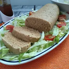 Un gustoso polpettone di tonno, affettato e servito su un letto di lattuga fresca con pomodorini.