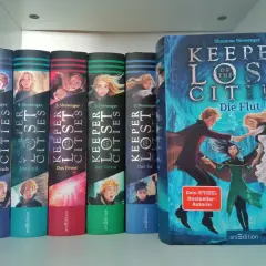 Die Bücherreihe "Keeper of the Lost Cities" mit Sophie als Hauptfigur. Mehrere Bände sind nebeneinander aufgestellt, der größte Band "Die Flut" steht rechts.