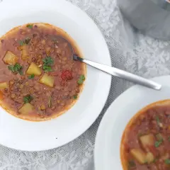 Herzhafte italienische Linsensuppe mit Kartoffeln und Kräutern in weißen Schalen, bereit zum Genießen.