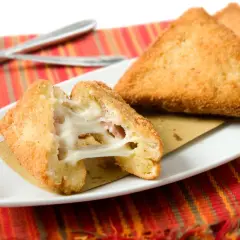Mozzarella in carrozza dorata e filante, preparata in friggitrice ad aria, servita su un piatto bianco con tovaglietta a righe rosse.