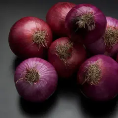 Un grupo de cebollas rojas sobre fondo oscuro. Se rumorea que el champú de cebolla tiene propiedades beneficiosas para el cabello.