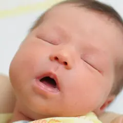 Śpiący noworodek z otwartymi ustami. Zwróć uwagę na napięcie mięśniowe u niemowlaka objawy, które mogą być subtelne.