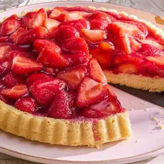 Ein saftiger Erdbeerkuchen, frisch belegt mit vielen roten Erdbeeren und glänzendem Tortenguss. Ein Stück ist bereits herausgeschnitten.