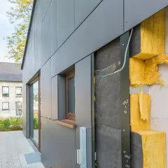 Isolation extérieur : vue rapprochée d'une façade en cours de construction, montrant l'isolant jaune et le revêtement gris. Le prix de cette isolation est un facteur clé pour les propriétaires.