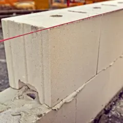 Czerwona nić wyznacza linię budowy, pokazując, ile bloczków betonowych na metr bieżący potrzeba do wzniesienia ściany.