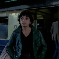 Kobieta w zielonej kurtce stoi przy pociągu. Scena z filmów Barbary Sass.