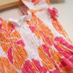 Close-up of a smocked garment with a floral pattern, showing how to sew with elastic thread for a gathered effect.
