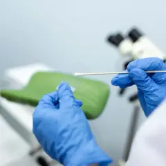 Ręce w niebieskich rękawiczkach przygotowują próbkę do analizy. Wynik biopsji tarczycy kategoria 3 jest kluczowy dla dalszego leczenia.