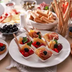 Idealne menu na 18 urodziny w domu: mini tartaletki z owocami, przekąski z szynką i oliwkami, paluszki grissini, ser i dżem.