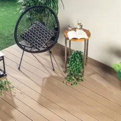Drewniana deska tarasowa to świetne rozwiązanie, co na balkon zamiast płytek. Wygodny fotel, stolik i latarenki tworzą przytulną atmosferę.
