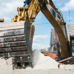Une pelleteuse jaune démolit une maison. Le prix de la démolition maison est en cours de calcul.