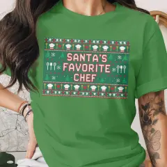 Grünes T-Shirt mit Weihnachtsmuster und der Aufschrift "Santa's Favorite Chef".