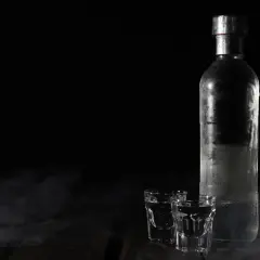 Chłodna butelka wódki i dwa kieliszki na ciemnym tle. Zastanawiasz się, jak długo może stać otwarta wódka?
