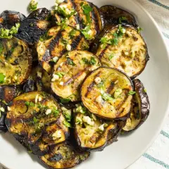 Rodajas de berenjenas a la plancha, doradas y tiernas, con ajo picado y perejil fresco. Un plato sencillo y delicioso.