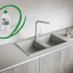 Butelka z zieloną nakrętką, zawierająca impregnat do zlewu granitowego, obok nowoczesnego zlewu i baterii.