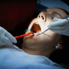Dentysta bada jamę ustną pacjentki. Czy antybiotyk pomoże na ropień zęba?