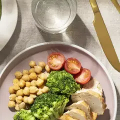 Assiette de poulet, brocolis, pois chiches et tomates, avec avocat et noix. Un repas équilibré pour un rééquilibrage alimentaire réussi.