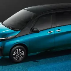 Elegancki, błękitny Nissan Serena z czarnym dachem prezentuje się nowocześnie na błyszczącym, niebieskim tle.