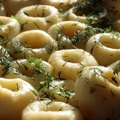 Kluski śląskie z koperkiem, ułożone na talerzu.