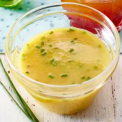 Ein Glas mit cremigem honig senf dressing, garniert mit Schnittlauch. Perfekt für Salate.