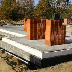 Na budowie widać fundamenty domu, płyty betonowe i sterty pustaków ceramicznych. To właśnie te pustaki, zwane potocznie chudziak, są podstawą ścian.