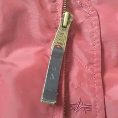 Zamek kurtki Alpha Industries z logo. Detale materiału i szwów, pomocne przy wyborze alpha industries rozmiarówka.
