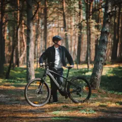 Mężczyzna z rowerem w lesie, gotowy na odkrywanie tras rowerowych Łeba.
