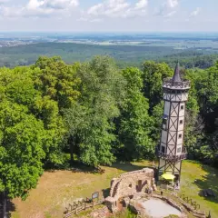 Wieża widokowa i ruiny zamku na tle zielonych gór Dolny Śląsk.